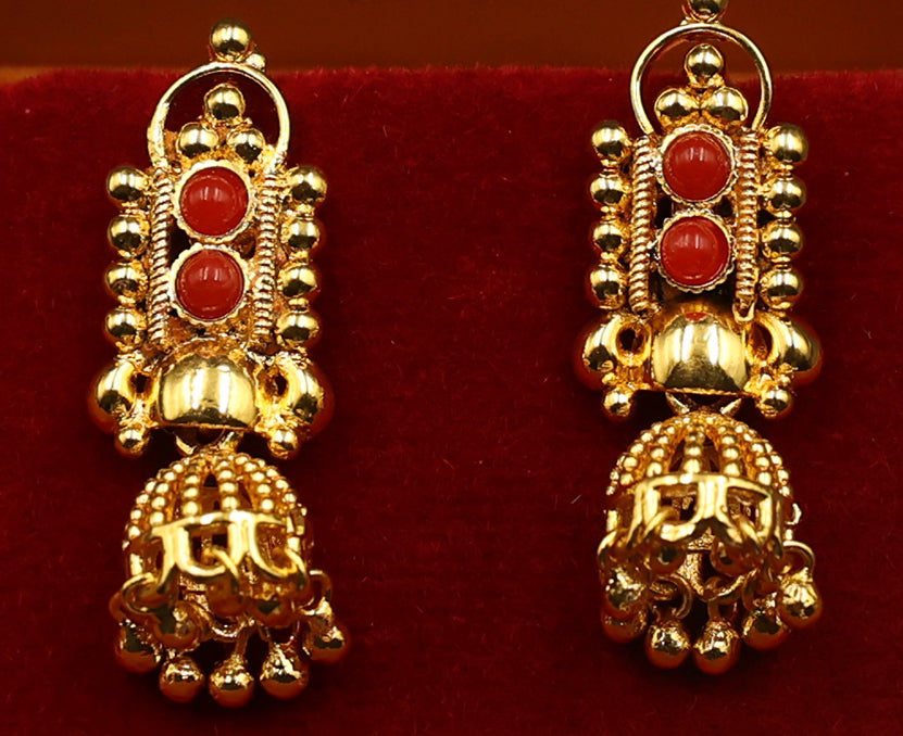 Gold earrings with red stones on a red background