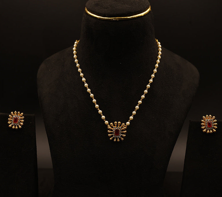 Pearl necklace with a pendant and matching earrings on a black background