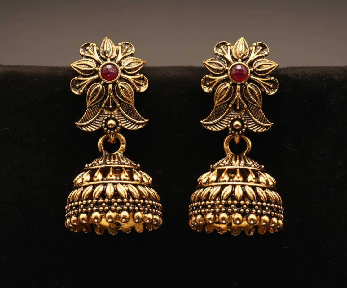 Gold earrings with floral top and bell-shaped bottom on a black background