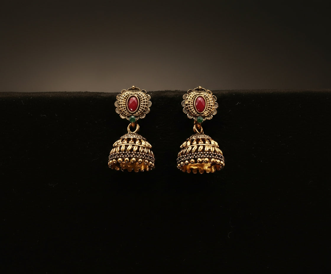 Gold earrings with red gemstones on a black background
