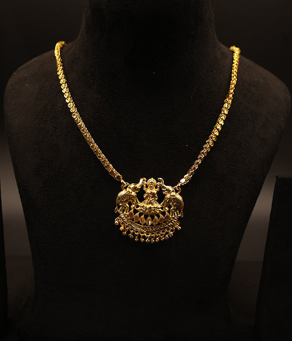 Gold necklace with a decorative pendant on a black mannequin against a dark background